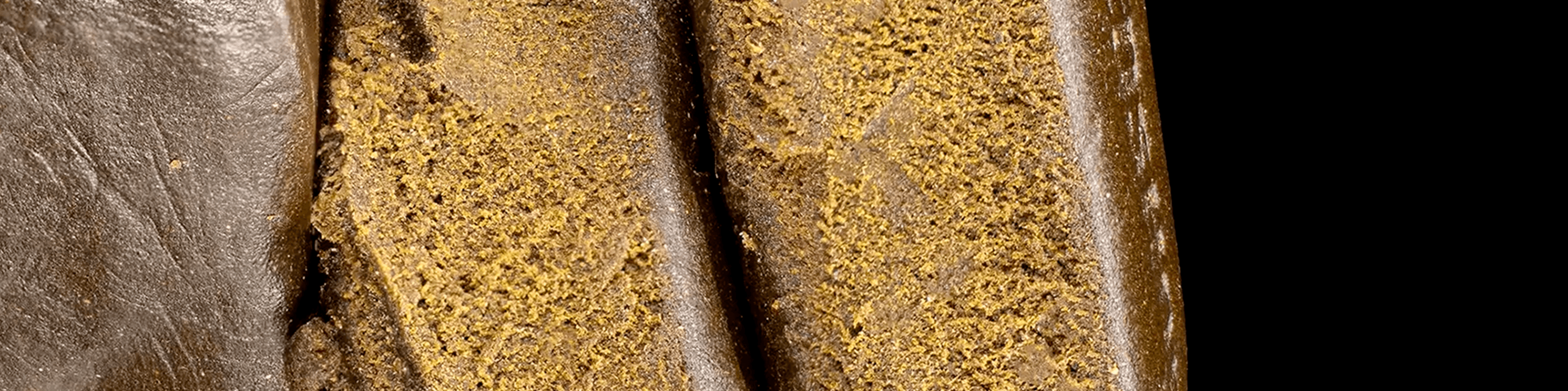 Close-up of THCA hash blocks with a dark brown exterior and a crumbly, golden interior texture.
