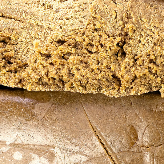 Close-up of a block of brownish cannabis hash on a textured surface