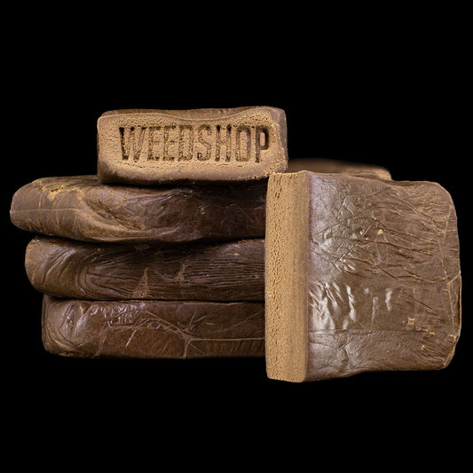 Stack of brown hash bars with 'WEEDSHOP' branding on a black background